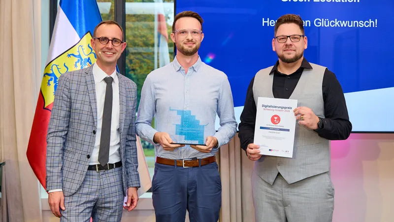 Digital minister Dirk Schrödter stands with two PROGEEK representatives in front of a screen reading "Green Ecolution, Herzlichen Glückwunsch!", one holds the glass trophy, the other the certificate