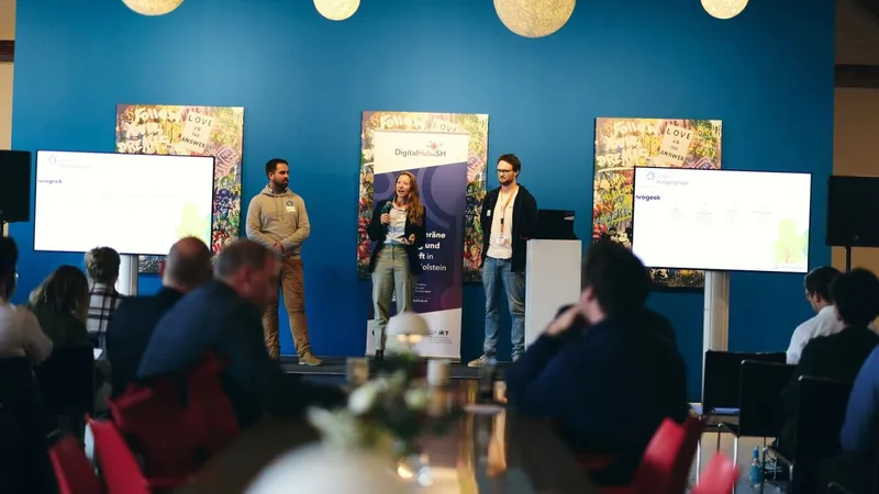 Three people present Green Ecolution on a stage, between two screens stands a DigitalHub.SH banner